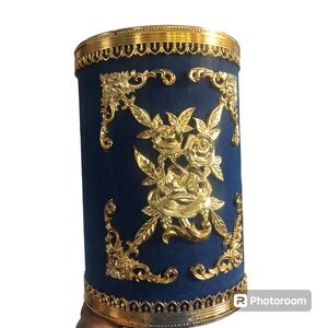 Light ornate gold tone plastic mold trim over a base deep royal blue trashcan